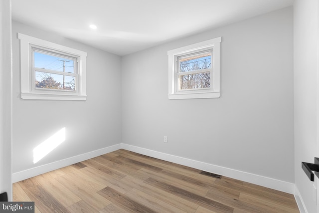 spare room featuring visible vents, wood finished floors, a wealth of natural light, and baseboards