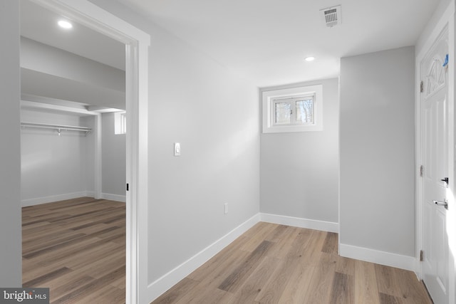 corridor with recessed lighting, visible vents, baseboards, and wood finished floors