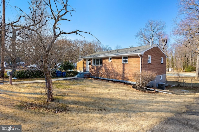 view of home's exterior featuring central air condition unit, a yard, fence, and brick siding