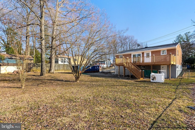 back of property with a yard, fence, a wooden deck, and stairs