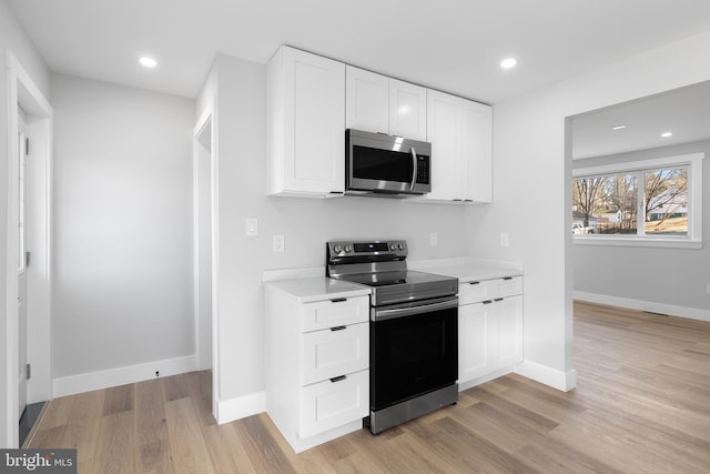 kitchen featuring appliances with stainless steel finishes, light countertops, light wood-style floors, white cabinetry, and recessed lighting