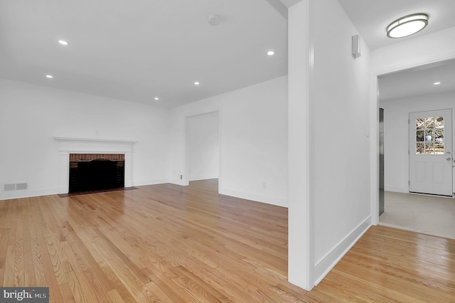 unfurnished living room with visible vents, recessed lighting, light wood finished floors, baseboards, and a brick fireplace