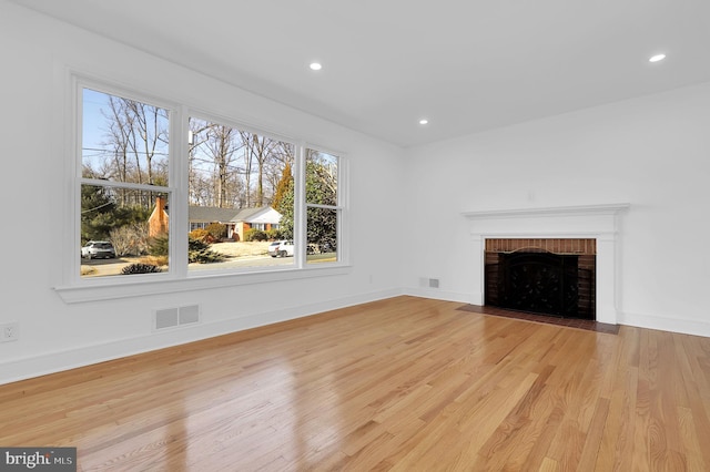 unfurnished living room with visible vents, wood finished floors, recessed lighting, baseboards, and a brick fireplace