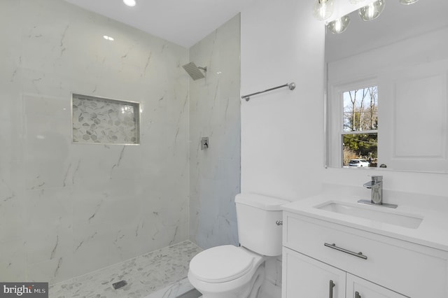 bathroom featuring a marble finish shower, toilet, and vanity