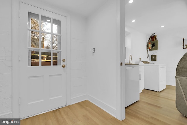 doorway to outside with light wood finished floors, washing machine and clothes dryer, baseboards, electric panel, and recessed lighting