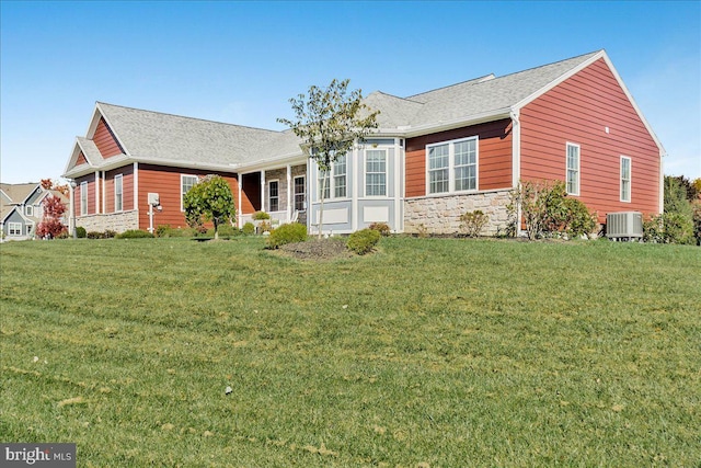 ranch-style home featuring cooling unit, stone siding, and a front lawn