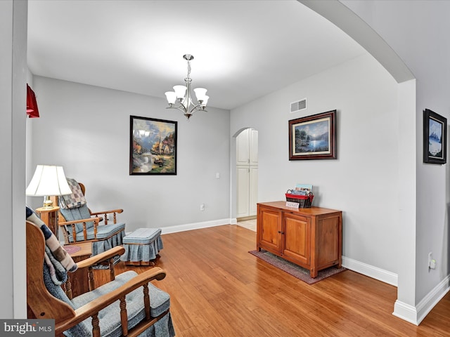 living area featuring arched walkways, baseboards, visible vents, and light wood-style floors