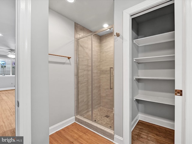 full bath with recessed lighting, wood finished floors, a ceiling fan, baseboards, and a shower stall