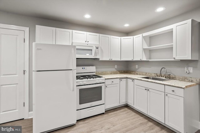 kitchen featuring white cabinets, white appliances, light wood finished floors, and a sink