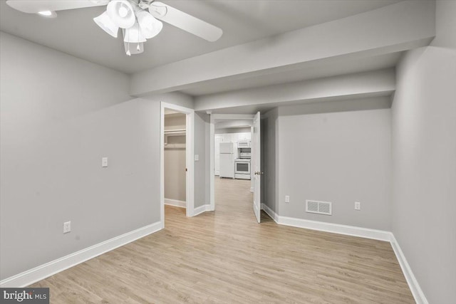 empty room featuring ceiling fan, light wood finished floors, visible vents, and baseboards