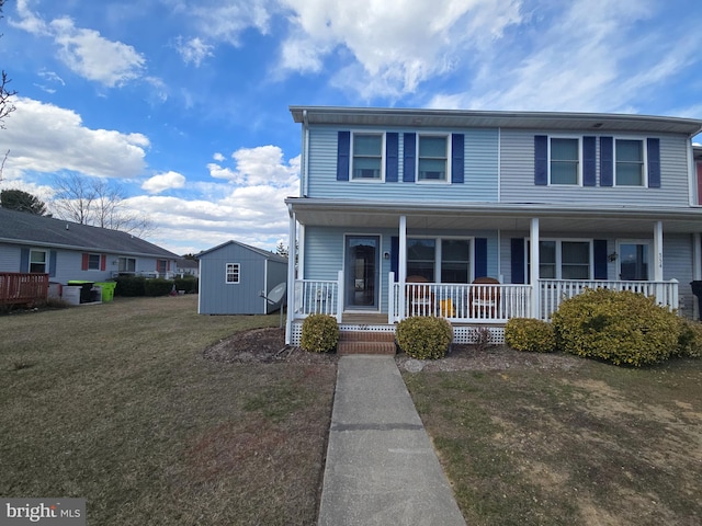 view of front of home featuring covered porch, a storage unit, a front lawn, and an outbuilding