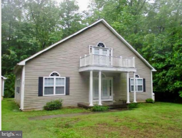 rear view of property featuring a balcony, covered porch, and a yard