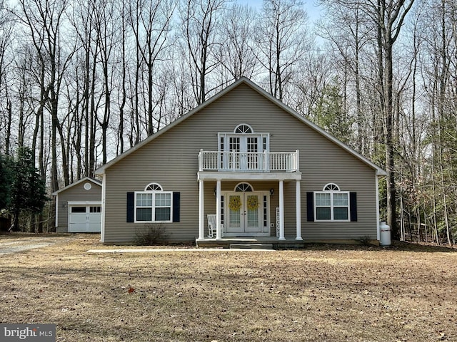 view of front of house featuring a garage, french doors, a balcony, an outdoor structure, and a porch