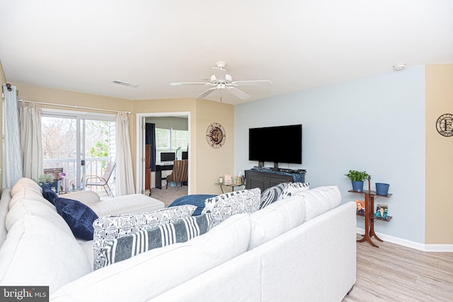 living area with light wood finished floors, a ceiling fan, visible vents, and baseboards