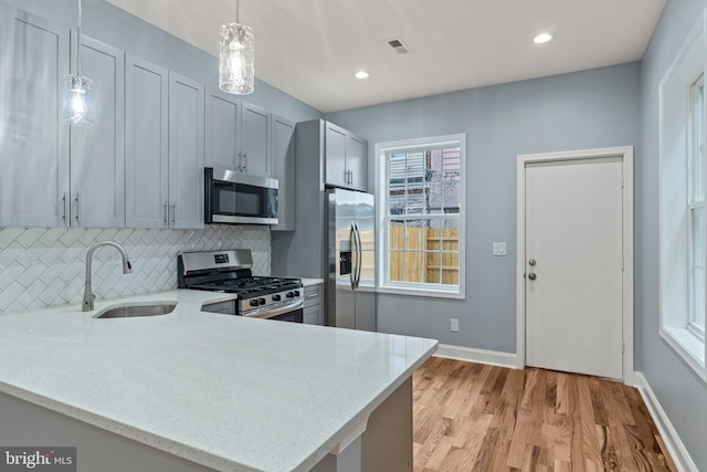 kitchen with tasteful backsplash, visible vents, stainless steel appliances, light wood-type flooring, and a sink