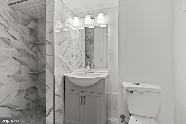 bathroom featuring toilet, tiled shower, and vanity