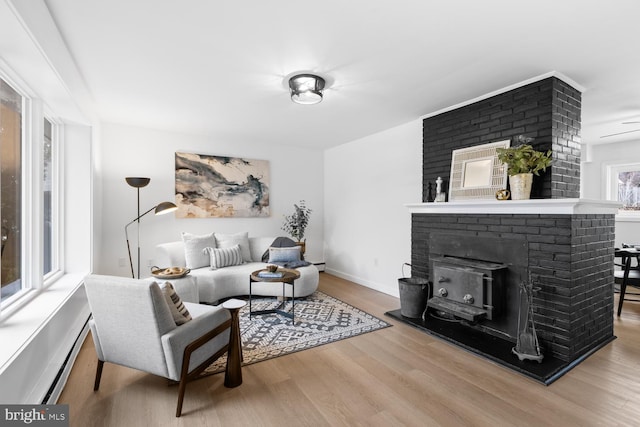 living room with a baseboard heating unit, wood finished floors, and baseboards