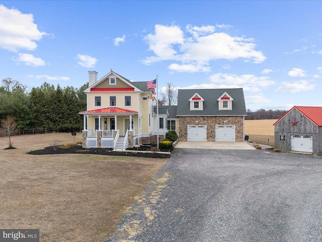 view of front of property featuring a garage, stone siding, an outbuilding, gravel driveway, and a porch