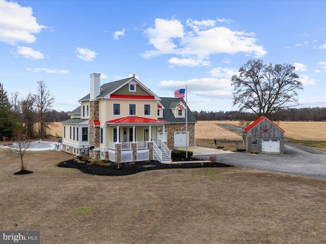 view of front facade with a front yard, covered porch, and gravel driveway