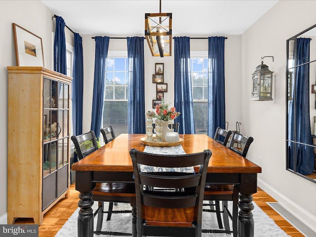 dining space with light wood-style flooring, baseboards, and a notable chandelier