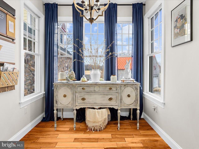 interior space with baseboards, light wood finished floors, and an inviting chandelier