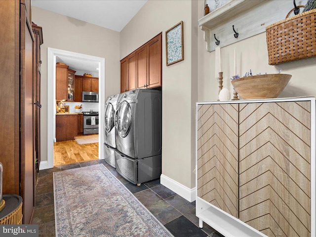 laundry area with cabinet space, baseboards, separate washer and dryer, and stone tile flooring