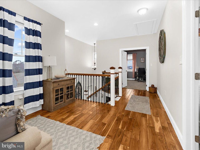 corridor featuring a wealth of natural light, hardwood / wood-style floors, an upstairs landing, and attic access