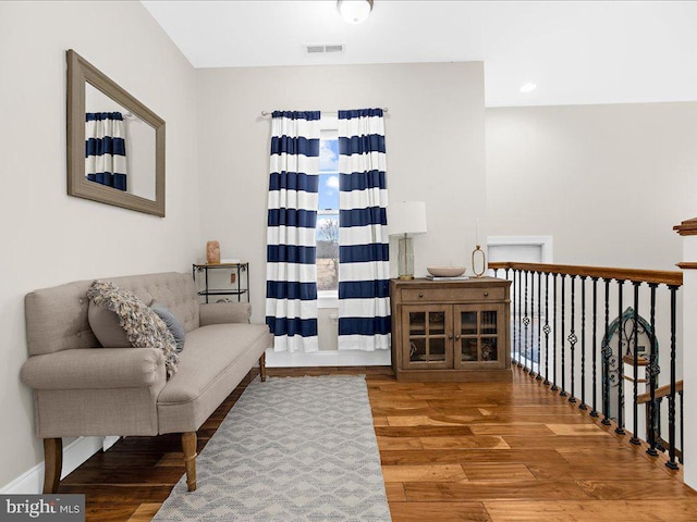 living area with wood finished floors, visible vents, and baseboards