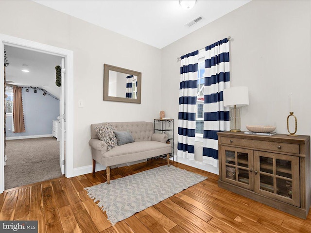 living area featuring wood-type flooring, visible vents, and baseboards