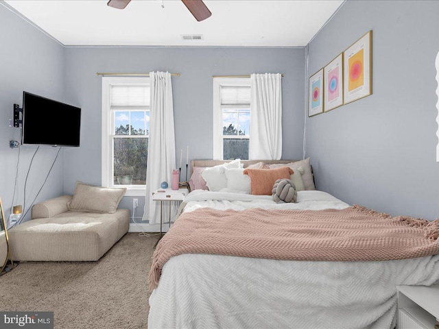 carpeted bedroom featuring a ceiling fan, visible vents, and multiple windows