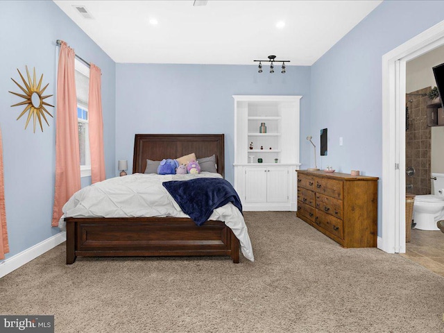 carpeted bedroom with baseboards, visible vents, and ensuite bath