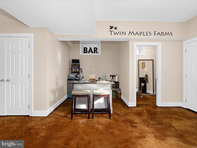 interior space featuring a breakfast bar, concrete floors, a kitchen island, and baseboards