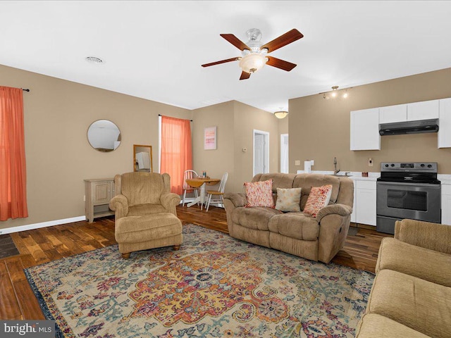 living room with dark wood-style flooring, a ceiling fan, and baseboards