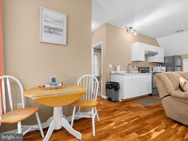 dining room featuring visible vents, vaulted ceiling, light wood-style flooring, and baseboards