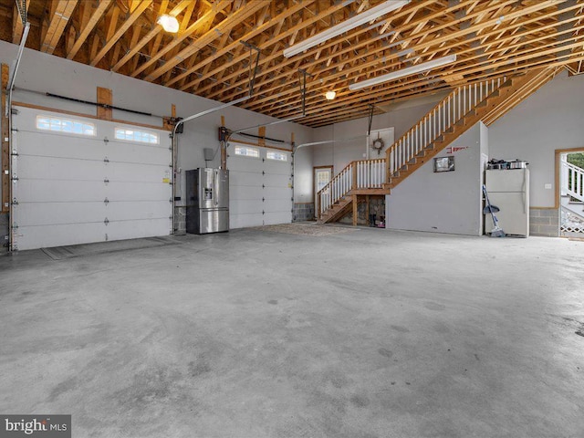 garage with stainless steel fridge and freestanding refrigerator