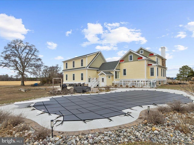 back of house with a covered pool, a chimney, and a patio