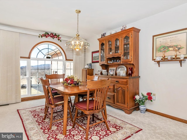 dining space with light carpet, an inviting chandelier, a mountain view, and baseboards