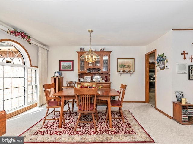 dining area with a chandelier, light carpet, and baseboards