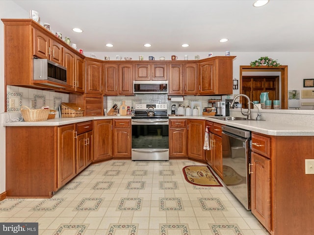 kitchen with stainless steel appliances, a peninsula, a sink, light countertops, and tasteful backsplash