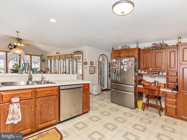 kitchen with brown cabinetry, lofted ceiling, stainless steel appliances, light countertops, and a sink