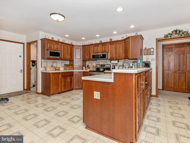 kitchen featuring stainless steel appliances, brown cabinetry, light countertops, and light floors