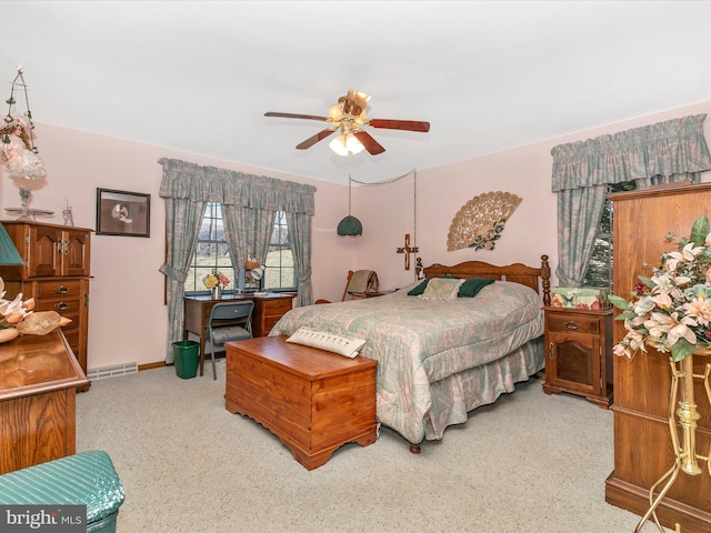 bedroom featuring a ceiling fan, light colored carpet, visible vents, and baseboards