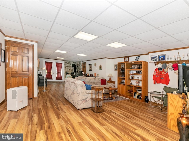 living area with a paneled ceiling, a wood stove, crown molding, and light wood-style flooring