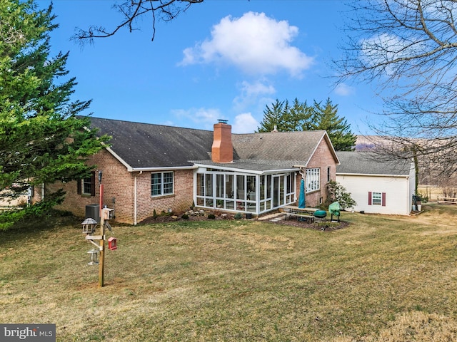 back of property featuring brick siding, a yard, a chimney, a sunroom, and cooling unit