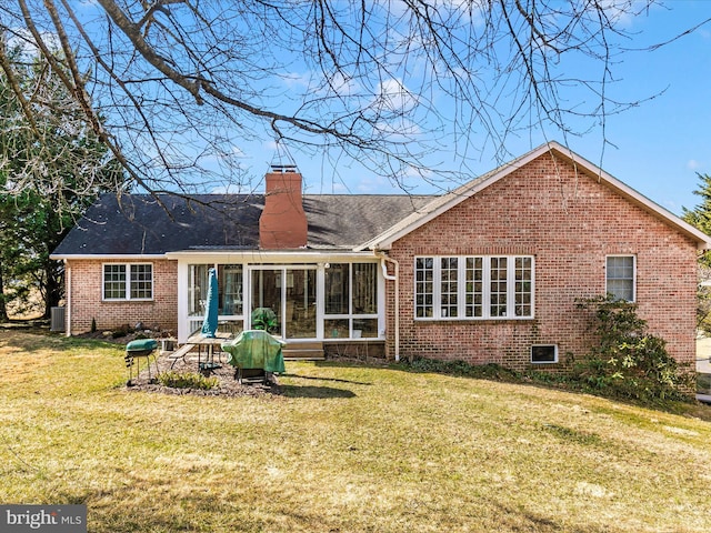 rear view of property with brick siding, a chimney, a lawn, a sunroom, and cooling unit