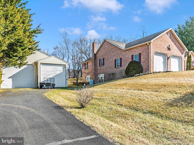 view of property exterior with a shingled roof, a chimney, a yard, an outdoor structure, and brick siding