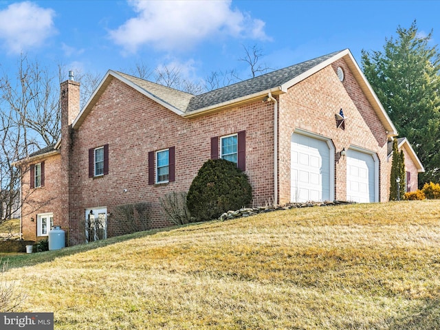 view of property exterior with an attached garage, brick siding, a shingled roof, a yard, and a chimney