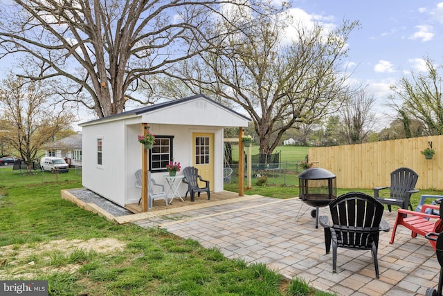 view of patio / terrace with an outdoor fire pit, fence, and an outbuilding