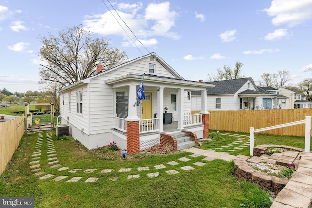 shotgun-style home featuring a porch, fence, central air condition unit, and a front lawn