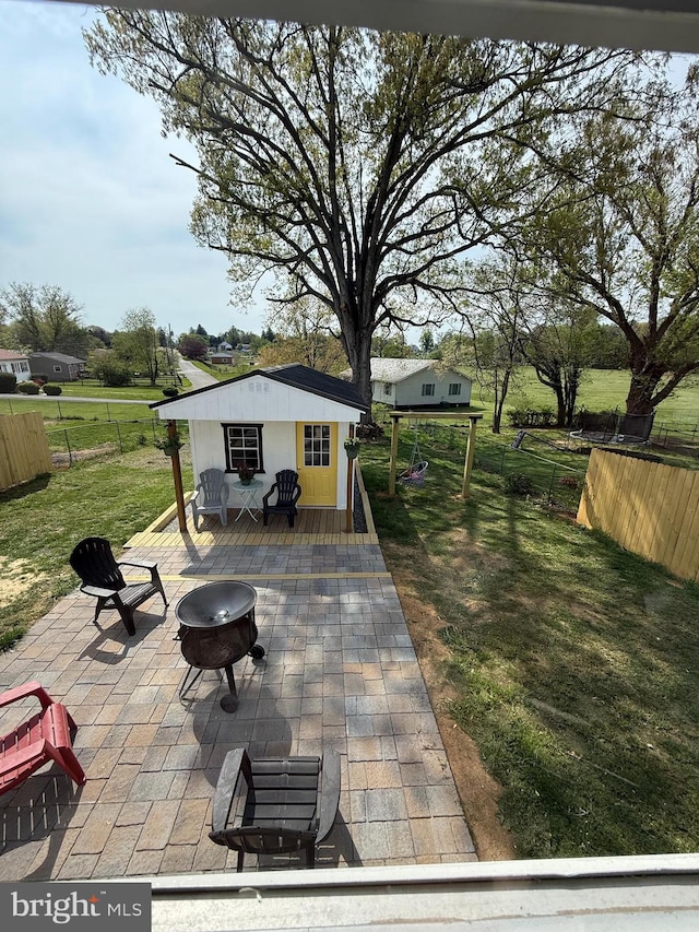 view of patio / terrace featuring a fire pit, fence, an outbuilding, and a deck